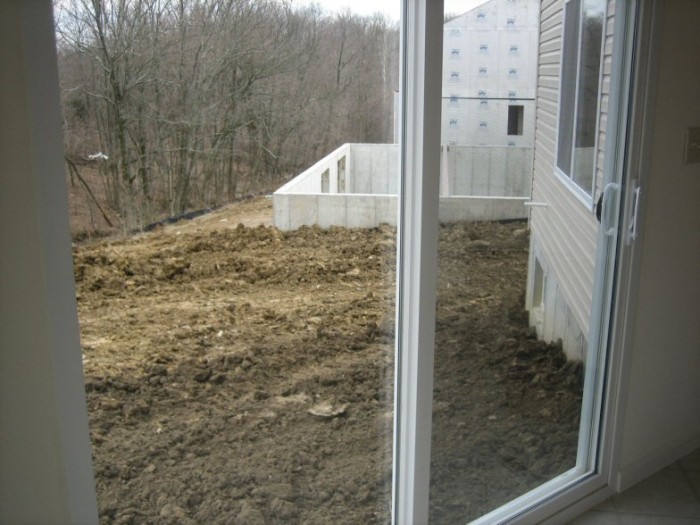 Dirt level under glass door will eventually be even with the bottom of the basement window (currently slopes up 1-2 more feet around the jut-out)